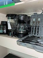 Photo showing the Hamilton Beach blender, Black and Decker coffee maker, and Koch Messer knife set in case all placed on a shelf.