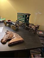 Cast iron horse and cart displayed with two horse head plaques on a table.