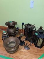 Full view of all items showing two brass cauldrons, oil lantern, four hanging lanterns, and candle holders grouped together on floor