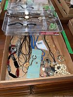 Two trays with five watches and various necklaces visible