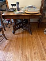 Full view of the wooden dining table displaying tabletop and leg details with items placed on top.