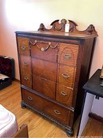 Front view of vintage highboy dresser showing four drawers and decorative top with carved details and original oval metal drawer pulls.