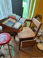 Photo showing vintage wooden school desk with visible wear and open drawer under seat. Various vintage books and tarot cards placed on the desk.