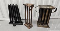 Front view of three antique metal candle molds showing multiple candle-shaped cavities and handles.