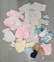 Full lot overview including various vintage kids and doll clothing garments arranged on floor.