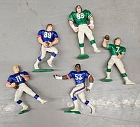 Five NFL action figures arranged on the floor showing front view with details of uniforms and poses.