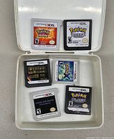 Top view of six Nintendo DS and 3DS game cartridges in plastic case showing front labels including various Pokémon titles and one Japanese language cartridge.