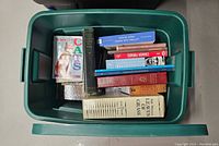 Overhead view of green tote filled with various vintage books including a collection about cats and Leaves of Grass by Walt Whitman