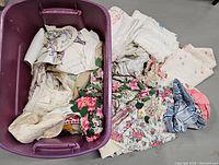 Tote filled with assorted antique and vintage linens including embroidered and crocheted pieces, photographed from above showing fabric contents