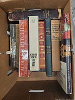 Box of vintage and antique books showing spines with various titles and bindings.