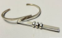 Sterling silver cuff bangle and money clip photographed together showing size and design details of both items.