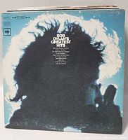 Close-up of Bob Dylan's Greatest Hits album cover showing distinctive blue background and silhouette profile of Bob Dylan.