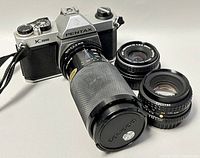 Front view of Pentax K1000 body with telephoto lens attached and two additional lenses beside