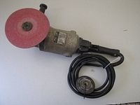 Image of Black and Decker angle grinder with 7 inch grinding disc attached and power cord coiled beside it