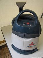Bissell Little Green ProHeat upholstery and carpet cleaner showing entire unit with hose and nozzle attachment.