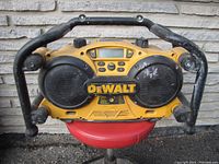 Front view of DeWalt 18 Volt radio showing speakers, control panel, and protective frame. Signs of wear and dirt present.