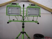 Twin-head fluorescent power work light mounted on green extendable tripod stand indoors