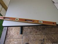 Top view photo of the wooden and metal carpenter's level placed horizontally on a table, showing the three bubble vials and brand logo.