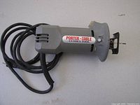 Single photo showing Porter Cable drywall cut out tool model 7499 lying flat with its power cord coiled beside it on a surface.