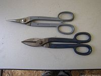 Two tin snip cutters placed on a flat surface for identification.