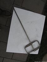 Top view of the 28 inch mortar mixer paddle with a 1/2 inch shaft lying on a white surface showing metal blade and shaft.