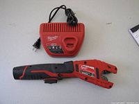 Milwaukee M12 copper tubing cutter, battery pack, and charger on white background