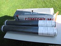 Three black foam underlayment rolls over a table with partially visible packaging box in background.