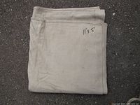 Folded natural canvas painter's drop sheet with handwritten 11'x5' marking on fabric.