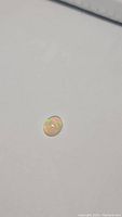 Single oval cabochon cut Ethiopian opal gemstone with visible multicolored flash on a plain white background.