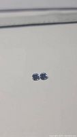 Close-up of two small round purple-blue tanzanite stones on a white background showing clarity and matching cut.