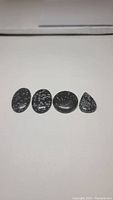 Four polished snowflake obsidian cabochons arranged in a row showing natural white snowflake pattern inclusions on black stone.