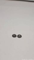 Pair of small oval black rutilated quartz cabochons on white background, showing size and overall appearance.