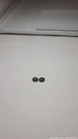 Two oval shaped jet black onyx stones side-by-side on a white background, clearly showing their size and matching nature.