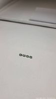 Four small oval cut mint green apatite gemstones laid in a row on a white flat surface, showing their clarity and color.