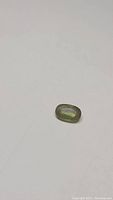 Top view of the oval sphene gemstone, showing elongated oval shape and translucent greenish-yellow color with internal inclusions.