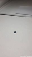 Blue sapphire gemstone placed on a plain surface for clear viewing, showing overall size and color.