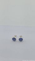 Front view of natural blue sapphire sterling silver stud earrings on white background.
