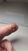 Close-up photo of natural citrine silver ring held between thumb and forefinger, showing oval cut gemstone and heart pattern in band