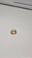 Oval cut natural golden citrine gemstone on a white background showing the size and clarity details.