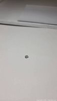 Photo showing the mint green sapphire from a distance on white background, small size visible.