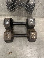 Pair of hexagonal 20 lbs dumbbells placed on a metal diamond plate surface, showing top view of both dumbbells side by side.