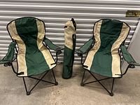 Photo showing two green and beige foldable camping chairs and one matching carrying bag placed between them.