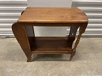 Image showing the wooden bench from the front, highlighting the top surface, lower shelf, and side spindles