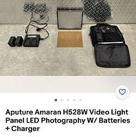 Overall kit contents laid out on floor surface including light panel, batteries, charger, diffuser, cables, and carrying case.