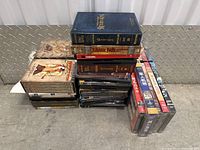 Stack of DVD cases including The Lord of the Rings: The Return of the King, Jurassic Park Adventure Pack, Cardinal, and other movies and sets.