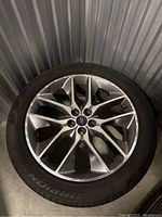 View of one alloy wheel with mounted tire, showing the tread and wheel design.