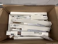 Top view of an open box filled with multiple IKEA MITTLED LED light strips and accessories in white retail packaging.