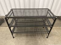 Full front view of black metal shoe rack with three shelves.