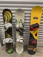 Front view of all three snowboards leaning against storage wall
