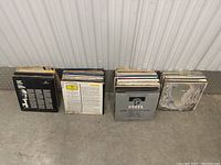 Photo showing three groups of vinyl record albums arranged side by side against a corrugated wall, highlighting the spines and covers of the albums including 'Evita'.